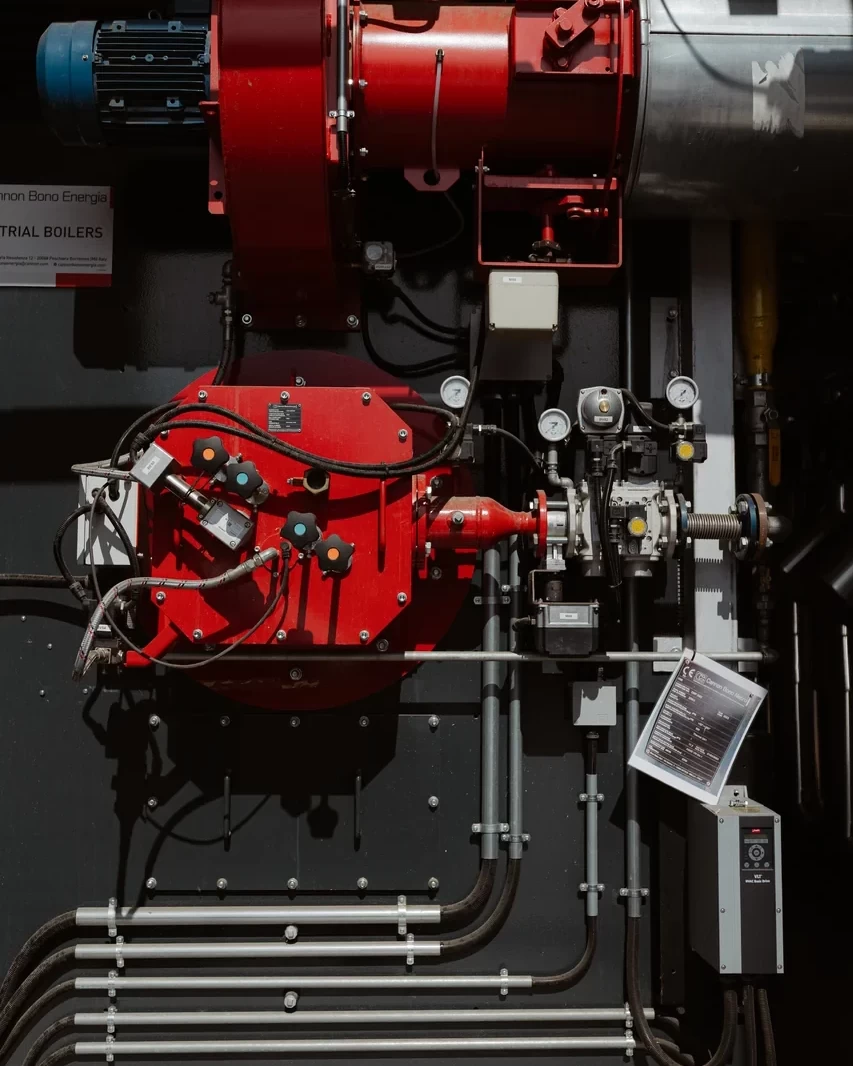 Bruciatore rosso con ventilatore, raccordi e strumenti di controllo su un generatore industriale