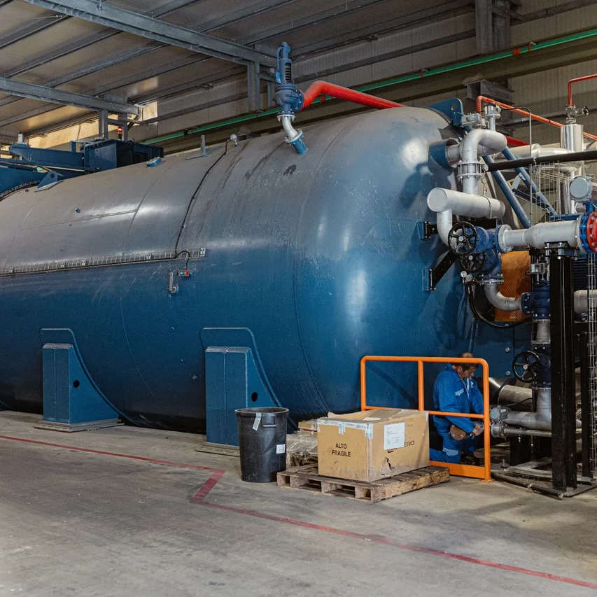 Caldaia industriale blu con tubazioni e componenti di servizio nel reparto tecnico