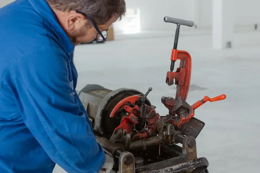Tecnico al lavoro su una tubazione con una macchina da banco