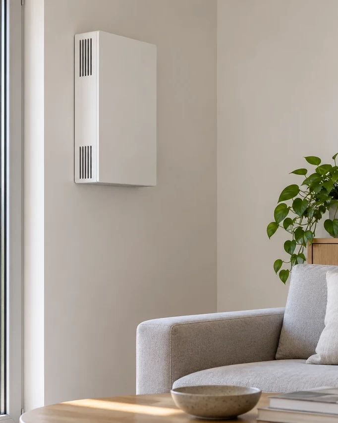 Unit&agrave; di ventilazione a parete installata nel soggiorno accanto a una finestra