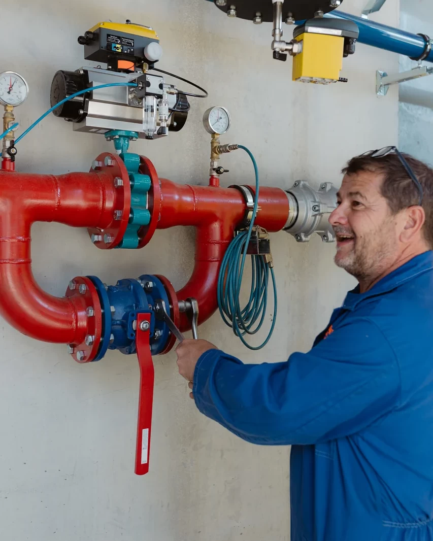 Tecnico controlla una valvola su una tubazione antincendio rossa